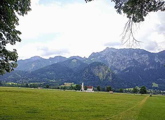 Kirche im Feld mit Bergen im Hintergrund