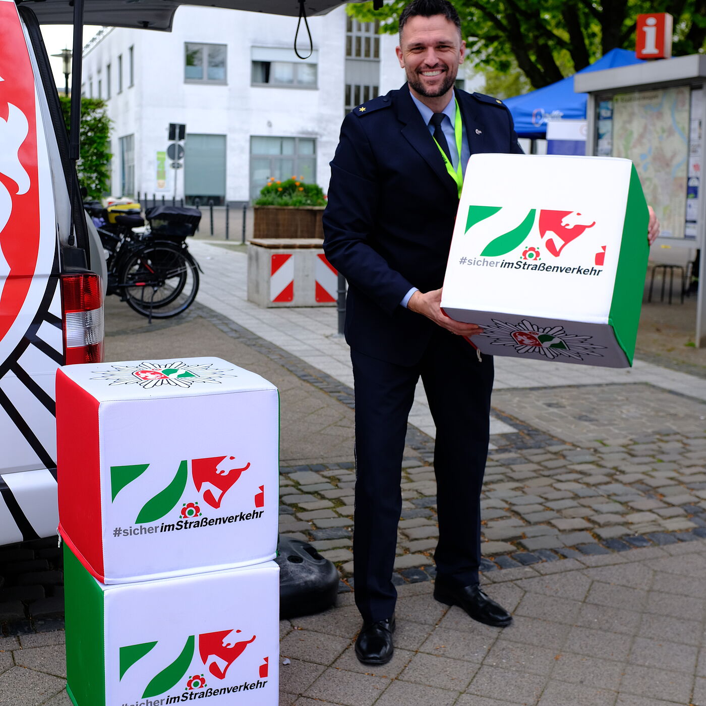 Die Polizei NRW packt die Verkehrssicherheit im Rahmen der Initiative #sicherimStraßenverkehr an. Ein Polizist hebt einen Kampagnenstein hoch. 